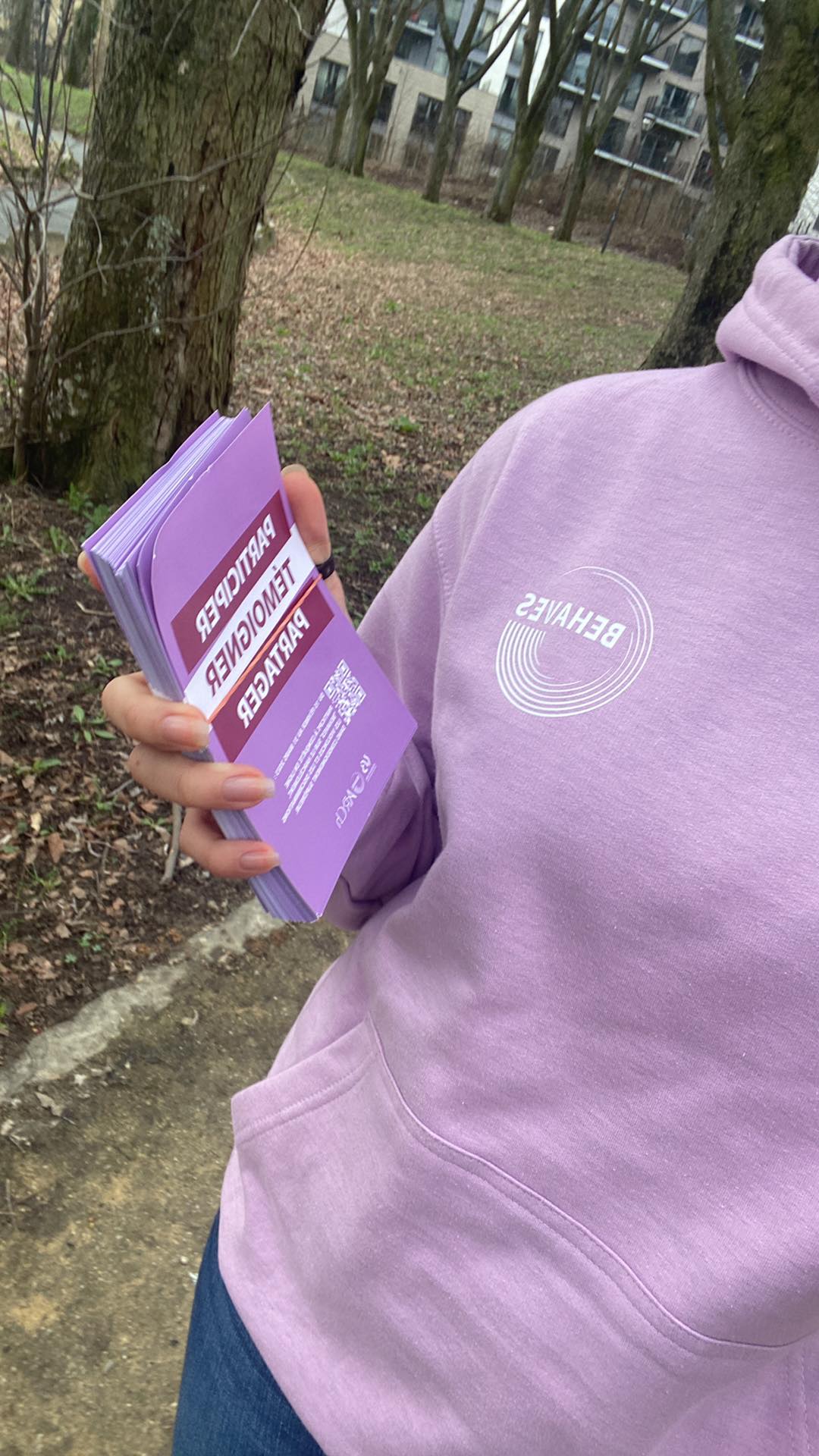 Flyers BEHAVES en main, hoodie de l'étude visible