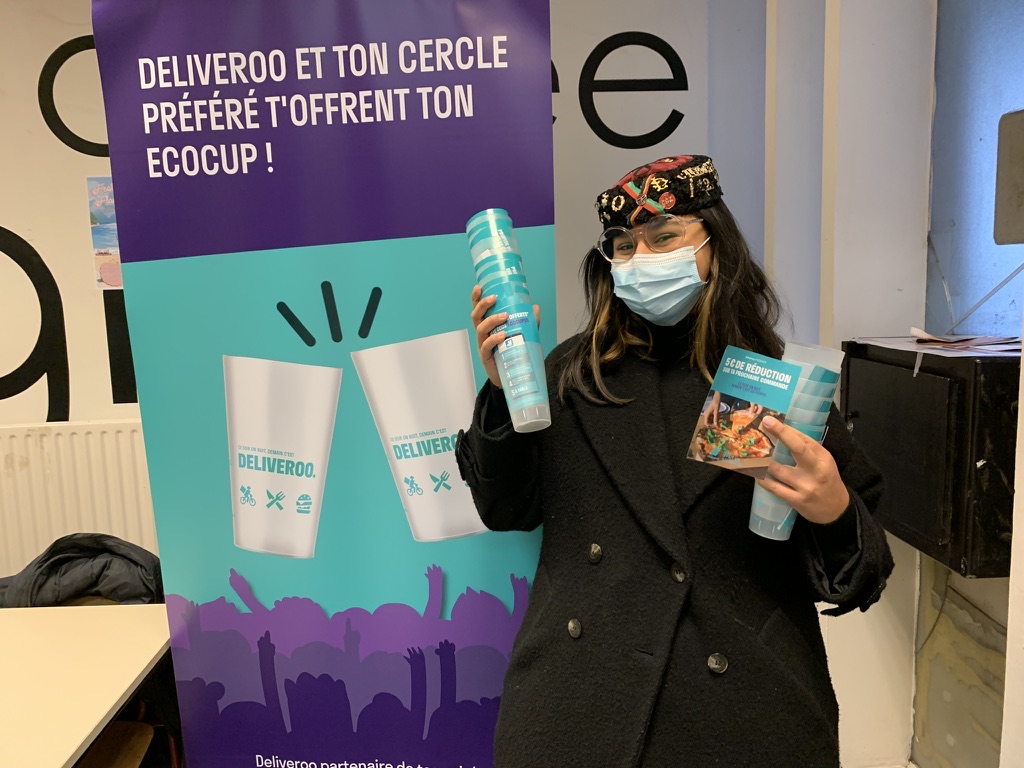 Étudiante devant le roll-up « Deliveroo et ton cercle préféré t'offrent ton écocup ! », écocup en main