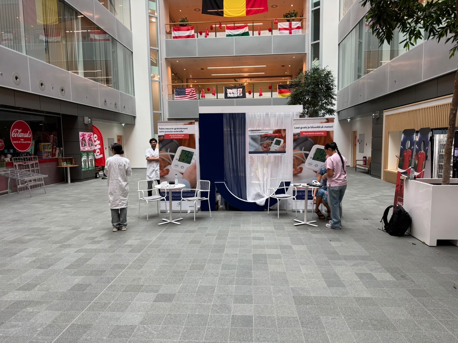 Stand de dépistage bilingue dans l'atrium d'un hôpital, ambassadeurs en blouse blanche