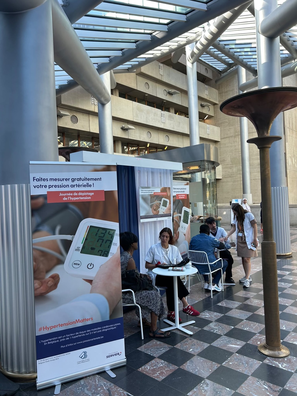 Stand « Faites mesurer gratuitement votre pression artérielle ! » dans le hall vitré d'un hôpital